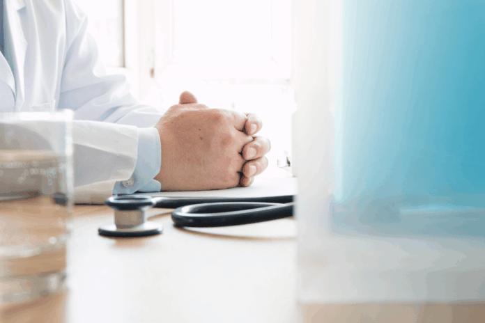 medico_apoya_manos_en_una_mesa